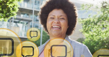 Bild der Botschaft Symbole über lächelnde afrikanisch-amerikanische Frau in der Stadt. Globale Verbindungen, Netzwerke, soziale Medien und digitales Schnittstellenkonzept digital generiertes Bild.