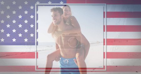 Téléchargez les photos : Femme blanche sur un homme hispanique ou latino, les deux souriant. Ils profitent d'un moment ludique sur une plage ensoleillée avec une toile de fond drapeau américain. - en image libre de droit
