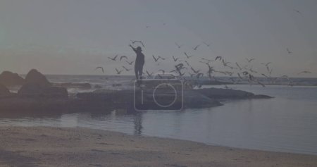 Photo for Bright spot of light against african american enjoying on the rocks near the sea. Travel and vacation concept - Royalty Free Image