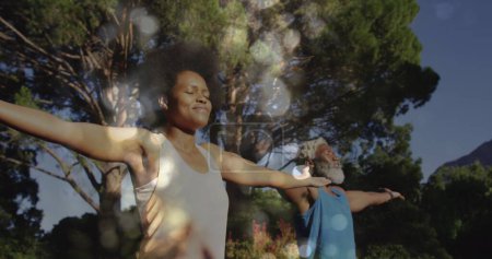 Téléchargez les photos : Image de taches lumineuses sur un couple afro-américain faisant du yoga, des étirements, du ralenti. Concept de sport, fitness et santé image générée numériquement. - en image libre de droit