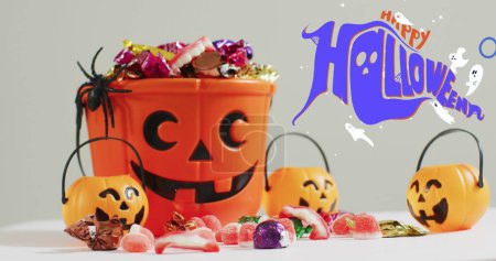 Téléchargez les photos : Joyeux texte d'Halloween bannière et fantômes icônes contre seau en forme de citrouille plein de bonbons d'Halloween. fête d'Halloween et concept de célébration - en image libre de droit