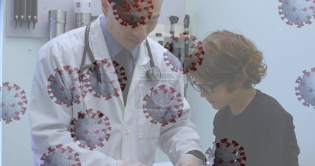 Téléchargez les photos : Image d'un médecin examinant un jeune patient hospitalisé avec des cellules de coronavirus flottant au premier plan. Covid 19 pandémie santé santé science médecine concept numérique composite - en image libre de droit