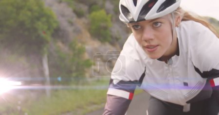 Imagen de manchas de luz sobre la mujer caucásica en bicicleta. bicicleta nacional para el día de trabajo y concepto de celebración de imagen generada digitalmente.