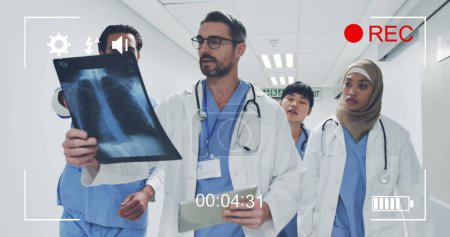 Téléchargez les photos : Image d'un portrait d'un groupe diversifié de médecins, vue sur un écran d'un appareil photo numérique en mode enregistrement avec icônes et minuterie 4k - en image libre de droit