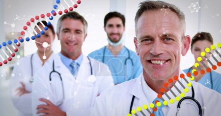 Téléchargez les photos : Image de brins d'ADN filant sur le portrait d'un groupe de médecins avec des stéthoscopes portant des blouses de laboratoire souriant à la caméra. Concept de médecine mondiale image générée numériquement. - en image libre de droit