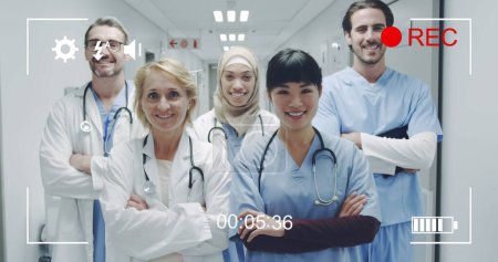 Téléchargez les photos : Image d'un portrait d'un groupe diversifié de médecins regardant vers la caméra et souriant, vu sur un écran d'un appareil photo numérique en mode enregistrement avec des icônes et minuterie 4k - en image libre de droit