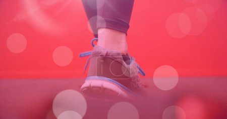 Foto de Imagen de manchas de luz sobre mujer caucásica caminando sobre fondo rojo. día de caminata y concepto de celebración imagen generada digitalmente. - Imagen libre de derechos
