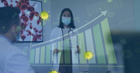 Photo for Image of yellow virus cells over biracial female doctor in face mask and graphs. Health, medicine, biology, science and covid 19 pandemic concept digitally generated image. - Royalty Free Image