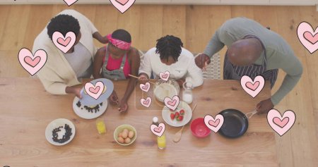 Téléchargez les photos : Image de cœurs roses sur de heureux grands-parents afro-américains et petits-enfants cuisinant à la maison. concept de famille, d'unité et de bien-être image générée numériquement. - en image libre de droit