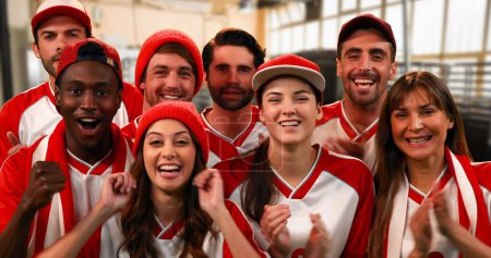 Téléchargez les photos : Vue de face d'un groupe de fans de sport portant des maillots rouges et blancs acclamant vivement - en image libre de droit