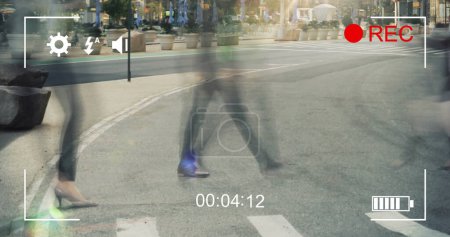 Image of commuters crossing a street in fast motion and cityscape, seen on a screen of a digital camera in record mode with icons and timer 4k