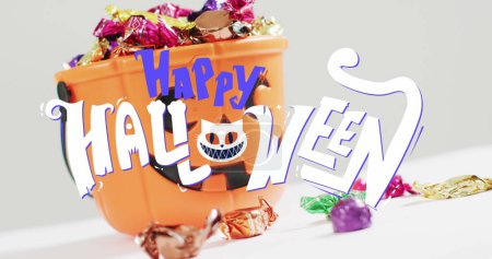 Foto de Imagen de texto feliz halloween con gato sobre cubo de calabaza naranja con dulces. halloween tradición y celebración concepto de imagen generada digitalmente. - Imagen libre de derechos