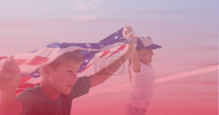 Photo for Caucasian brother and sister with american flags running at the beach. national siblings day awareness concept - Royalty Free Image