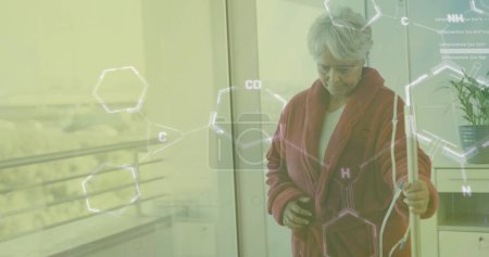 Téléchargez les photos : Image de formule chimique sur une patiente biraciale âgée marchant avec goutte-à-goutte. Médecine, santé et concept d'interface numérique, image générée numériquement. - en image libre de droit
