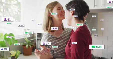 Photo for Image of social media icons and numbers over lesbian caucasian couple at home. Global social media, data processing and digital interface concept digitally generated image. - Royalty Free Image