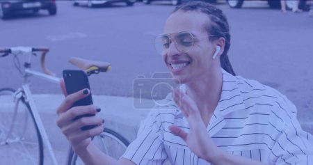 Téléchargez les photos : Image de taches de lumière sur l'homme biracial heureux en utilisant un smartphone. Journée nationale du vélo au travail et concept de célébration image générée numériquement. - en image libre de droit