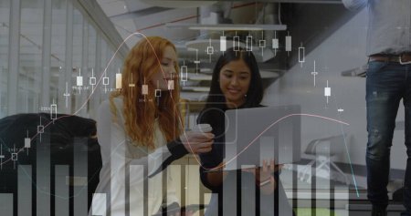 Photo for Digital composite of multi-racial businesswomen in an office looking at a laptop and graphs over them - Royalty Free Image