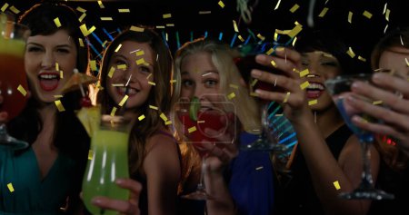 Téléchargez les photos : Composite numérique d'un groupe diversifié d'amies célébrant autour d'un verre dans un club tandis que les confettis d'or tombent à l'écran 4k - en image libre de droit