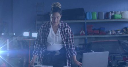Bild von leuchtendem Licht über einer Frau in der Werkstatt. Arbeitstag, Arbeit, Arbeiter, Tradition und Festkonzept digital generiertes Image.