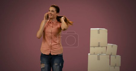 Photo for Image of woman talking on smartphone with stack of boxes on red background. global shipping and technology concept digitally generated image. - Royalty Free Image
