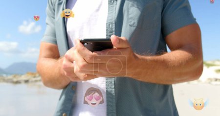 Photo for Image of emoticons over midsection of caucasian man using smartphone outdoors. global connections, social media, technology and digital interface concept digitally generated image. - Royalty Free Image