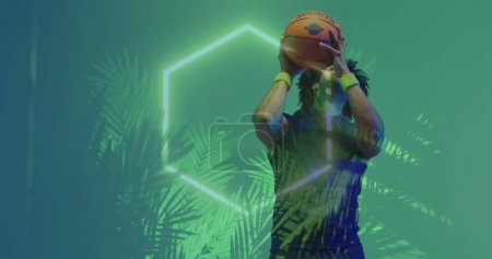 Image of planta with neon pattern and biracial basketball player. Sports, competition, image game and communication concept digitally generated image.