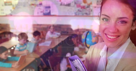Imagen compuesta de coloridos puntos de luz contra la profesora caucásica sonriendo en clase. escuela y concepto de educación