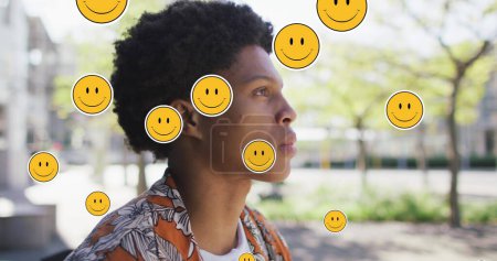 Bild von Emoji-Symbolen über einem Afroamerikaner, der Kaffee trinkt. Globales Geschäfts- und digitales Schnittstellenkonzept digital generiertes Bild.