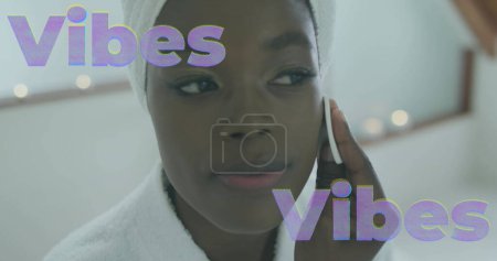 Photo for Image of vibes text in lilac over happy african american woman cleansing face at home. relaxation, health and wellbeing concept digitally generated image. - Royalty Free Image