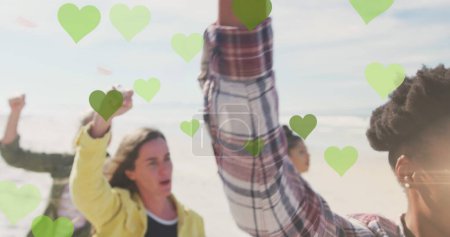 Image of green hearts over diverse people rising fists. Global education and learning concept digitally generated image.