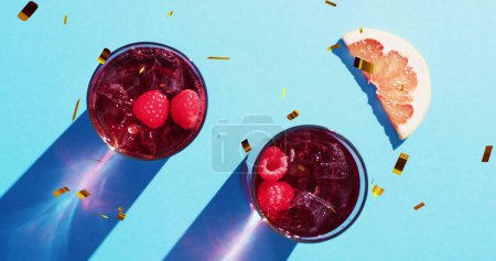 Téléchargez les photos : Image de confettis tombant et cocktails sur fond bleu. Fête, boisson, divertissement et concept de célébration image générée numériquement. - en image libre de droit