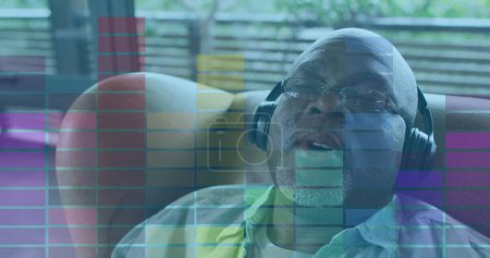 Image of audio eq meter over senior african american man relaxing at home with headphones on. retirement lifestyle, relaxation, music and technology concept digitally generated image.