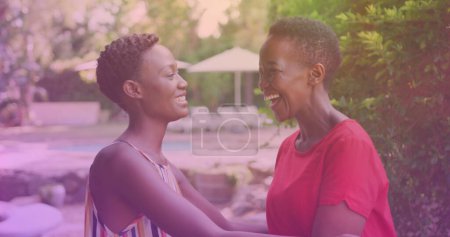 Téléchargez les photos : Two african american sisters hugging each other at a resort. national siblings day awareness concept - en image libre de droit