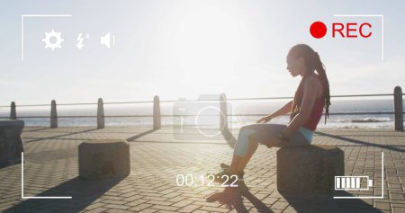 Téléchargez les photos : Interface d'appareil photo numérique contre femme afro-américaine fatiguée en forme assis sur la promenade. sport, fitness et concept technologique - en image libre de droit