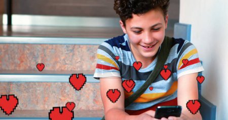 Digitalkompositionen eines kaukasischen Jungen, der lächelnd auf der Treppe sitzt, während er SMS schreibt, und digitale Herzen fliegen im Vordergrund 
