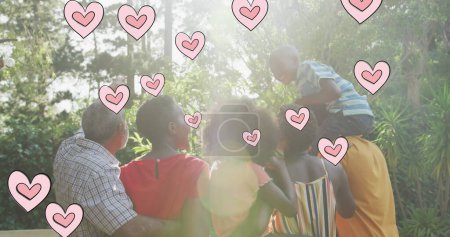 Foto de Imagen de corazones sobre la feliz familia afroamericana multigeneracional en el jardín. vida familiar, amor y naturaleza concepto de imagen generada digitalmente. - Imagen libre de derechos