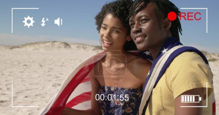 Photo for Image of a young biracial woman and a young African American man wrapped in an American flag, seen on a screen of a digital camera in record mode with icons and timer 4k - Royalty Free Image
