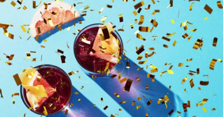 Téléchargez les photos : Image de confettis tombant et cocktails sur fond bleu. Fête, boisson, divertissement et concept de célébration image générée numériquement. - en image libre de droit