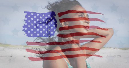 Foto de Imagen de la bandera de los estados unidos de América sobre la mujer biracial en la playa. Patriotismo americano, diversidad y tradición concepto de imagen generada digitalmente. - Imagen libre de derechos