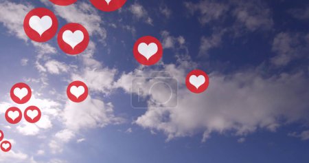 Foto de Múltiples iconos rojos del corazón flotan contra un cielo azul con nubes. Los corazones simbolizan el amor y el afecto, ambientados en un sereno cielo diurno. - Imagen libre de derechos