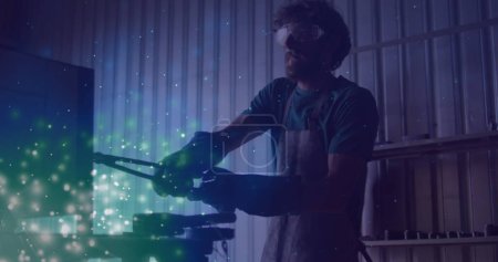 Image of glowing lights over caucasian man working in workshop. labor day, work, workers, tradition and celebration concept digitally generated image.