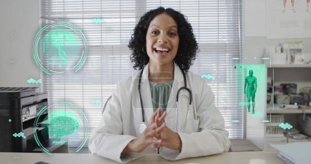 Image of science icons and data processing over biracial female doctor having image call. Medicine, technology and digital interface concept, digitally generated image.