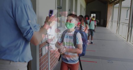 Foto de Imagen de la célula coronavirus con los escolares enmascarados desinfectando las manos antes de la clase. Salud y protección durante coronavirus covid 19 pandemia, imagen generada digitalmente. - Imagen libre de derechos