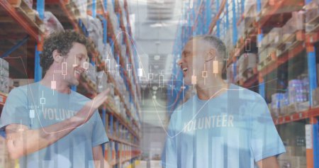 Statistical data processing over two caucasian male volunteers high fiving each other at warehouse. logistics and transportation business concept