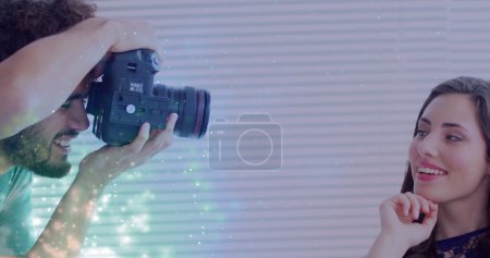 Photo for Image of sparkles over caucasian male photographer and female model taking photos. photography, optics and hobby concept digitally generated image. - Royalty Free Image