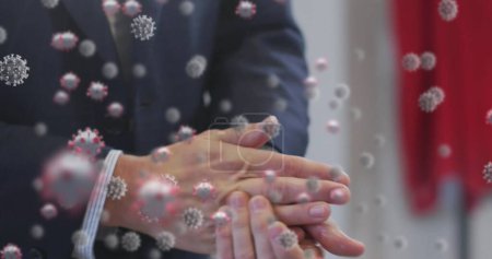 Image of covid 19 cells floating over midsection of businessman washing his hands. Healthcare and protection during coronavirus covid 19 pandemic, digitally generated image.