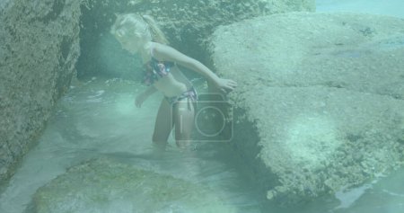 Photo for Glowing blue spots of light against caucasian girl walking close to the rocks near the sea. Travel and vacation concept - Royalty Free Image