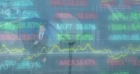 The image shows a businessman holding a blue umbrella and looking at a stock market display with green, red, and blue stock market numbers and graphs the price of the stocks is shown to be constantly changing