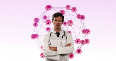 Téléchargez les photos : Image composite numérique de médecin masculin avec stéthoscope debout avec ses bras croisés sur Globe d'icônes numériques roses filant sur fond rose. Réseau mondial et concept de recherche médicale - en image libre de droit