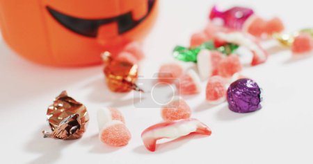 Foto de Feliz pancarta de Halloween contra el cubo en forma de calabaza lleno de caramelos de Halloween. Halloween festividad y concepto de celebración - Imagen libre de derechos